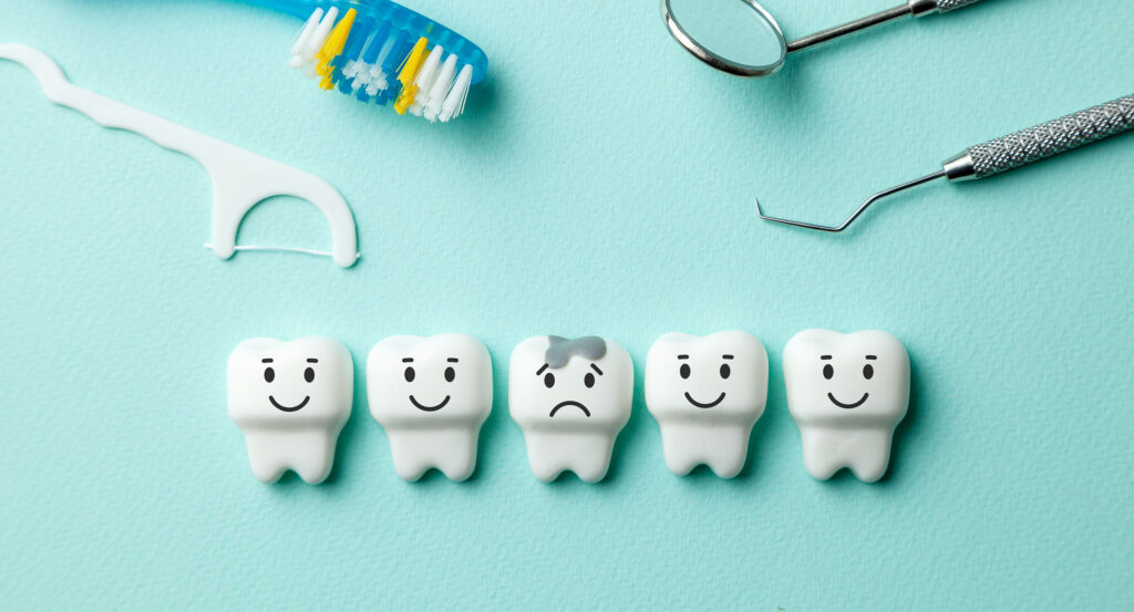 Toothbrush, floss, and dental tools above cartoon teeth, one with decay, illustrating cavity risk and oral hygiene care